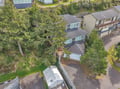 Aerial view showcasing the property nestled in a peaceful residential neighborhood surrounded by mature trees and nearby coastal homes.