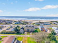 Stunning aerial view of coastal vacation properties nestled between ocean waves and sandy beach, offering prime beachfront location.