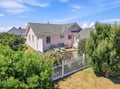 This charming pink cottage is tucked into a peaceful coastal neighborhood, surrounded by lush greenery and framed by a classic white picket fence—your perfect seaside retreat awaits.