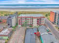 Aerial view of beachfront property buildings with direct ocean access and nearby coastal amenities.