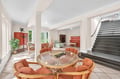 Relax in this elegant living space with warm wood furnishings, soaring beamed ceilings, and natural light flowing through large windows.
