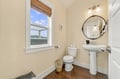 Freshen up in your elegant guest bathroom, where a pedestal sink and decorative mirror add charm, and natural light frames peaceful hillside views through the window.
