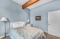 Unwind in your peaceful bedroom featuring a plush bed, charming exposed beam, and soft blue walls that create the perfect sanctuary for rest.