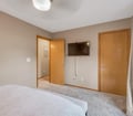 Your bedroom features soft neutral tones, plush carpeting, and a wall-mounted TV for your entertainment. A spacious wardrobe provides plenty of storage for your belongings.