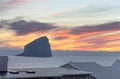 Dramatic sunset paints the sky in vibrant hues over the iconic Haystack Rock and Pacific Ocean coastline.