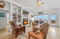 Unwind in your cozy living room, where plush seating invites relaxation by the warm fireplace. Natural light pours through glass doors leading to a private deck, framing peaceful views of the surrounding landscape.