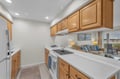 Your kitchen features warm wood cabinets and crisp white countertops, perfect for preparing meals while staying connected to the living area.