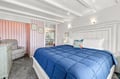 Your cozy bedroom features a welcoming white-framed bed topped with a plush blue comforter, elegant wall paneling, and charming vintage touches that create a peaceful retreat for restful nights.