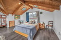 Drift off under soaring wood beams and skylights in your charming attic retreat, where rustic warmth meets modern comfort.