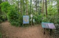Hiking trails and natural wetlands near the property, shown on informational signage at a trailhead surrounded by lush forest.