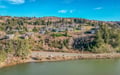 Scenic hillside neighborhood overlooks tranquil waters, offering peaceful residential setting surrounded by natural landscape and rolling hills.