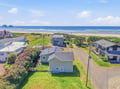 Aerial view of a coastal rental property nestled in a quiet beachfront neighborhood, with sandy shores and scenic ocean waters just steps away.