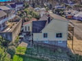 Aerial view of the property nestled in a charming residential neighborhood with tree-lined streets and coastal community character.