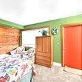 Step into a vibrant bedroom where playful green walls meet warm wood accents, creating a cheerful retreat. Rest easy on the quilted bed, surrounded by thoughtful storage and cozy carpet underfoot.