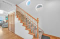 Beautiful wooden staircase with warm natural light streaming through round windows, leading you to your upstairs retreat.