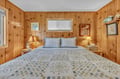 Drift off in your cozy knotty pine bedroom, where warm wood walls and soft lighting create the perfect rustic retreat for peaceful nights.