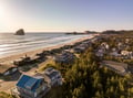 Stunning coastal community with pristine beach, dramatic rock formations, and charming homes nestled among lush trees.