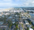 Aerial view of a coastal town nestled between ocean beaches and a winding river, surrounded by natural landscape and residential neighborhoods.