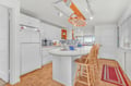 Your bright kitchen features a spacious island perfect for morning coffee and meal prep, with cheerful orange accents creating warmth.