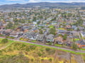Aerial view of the charming coastal neighborhood showcasing residential streets with rolling hills and forested landscape in the background.