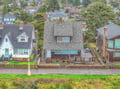 Charming coastal cottage nestled in a tree-lined neighborhood, featuring a welcoming deck and surrounded by classic beach town character.