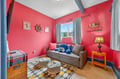 Your cozy retreat features vibrant coral walls, a comfy sofa, and cheerful nautical touches that create the perfect spot to unwind after exploring.