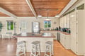 Gather around this spacious kitchen island, perfect for preparing your meals or enjoying a casual breakfast together. The warm wood-beamed ceiling and natural light from surrounding windows create a welcoming space where you can feel right at home.