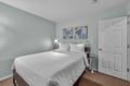 Sink into crisp white linens in your serene bedroom, where soft mint walls and tropical artwork create a peaceful retreat for restful nights.