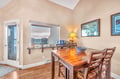 Your elegant dining space features a polished wood table perfect for meals, while the adjacent patio beckons with coastal chairs.