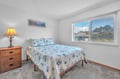 Drift off to sleep in your cozy bedroom with ocean-themed bedding and peaceful neighborhood views through the bright window.