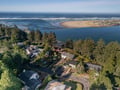 Aerial view of coastal properties nestled between forested landscape and pristine shoreline, showcasing the peaceful residential area near sandy beaches.