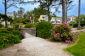 Charming coastal neighborhood with blooming gardens and tree-lined paths creating a peaceful retreat setting.