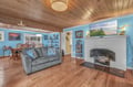 Sink into the plush sofa by your cozy fireplace, where warm wood ceilings and cheerful blue walls create the perfect gathering spot.