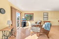 Sink into plush wicker seating while natural light pours through your balcony door. The cozy space invites you to unwind with a book or simply enjoy the peaceful treetop views framed by warm wood accents.