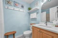 Step into your coastal-themed bathroom where soft blue walls and beach artwork create a serene retreat for your daily routines.