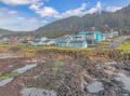 Coastal community nestled between forested hills and rocky tidal pools, showcasing the natural beauty surrounding the area.