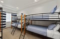 Sleep soundly in your nautical-themed bunk room, where crisp blue-striped bedding and cheerful white walls create the perfect cozy retreat.