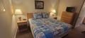 Your peaceful bedroom features a comfortable queen bed with nautical-themed linens, soft bedside lighting, and a TV for your entertainment. Everything you need to unwind after a day of adventure.