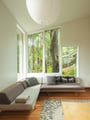 Unwind in your bright corner of tranquility, where floor-to-ceiling windows frame leafy trees and a sleek sectional invites relaxation.