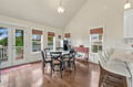 Gather around the table in this bright, inviting dining space where natural light streams through large windows and French doors open to your outdoor escape. Warm wood floors and coastal charm set the scene for memorable meals together.