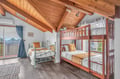 Your kids will love this cozy loft bedroom with rustic wood beams, featuring both a bunk bed and single bed for flexible sleeping arrangements.