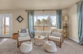 Unwind in your peaceful sitting area with cozy armchairs and soft textures, where natural light flows through large windows.