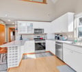 Step into your bright, airy kitchen with soaring ceilings and plenty of counter space for preparing meals together. Natural light pours through tall windows, illuminating crisp white cabinets and modern appliances ready for your use.