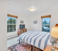 Wake up to natural light streaming through large windows that frame glimpses of greenery. Your cozy bedroom awaits, dressed in crisp nautical stripes and vintage touches, with peaceful views to start each morning refreshed.