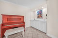 Discover your creative side with a charming red piano and convenient wet bar setup for entertaining.