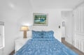 Sink into soft blue linens in your peaceful bedroom retreat, where gentle lamplight and coastal artwork create the perfect atmosphere for restful nights.
