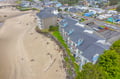 Aerial view of a beachfront property located in a charming coastal neighborhood, with direct beach access and surrounded by local streets and amenities.