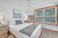 Rest peacefully in your serene bedroom featuring crisp linens, warm wood accents, and large windows overlooking lush greenery.