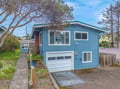 Charming coastal property with distinctive blue siding and convenient garage parking in a peaceful residential neighborhood.