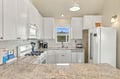 Your bright, fully-equipped kitchen invites you to cook and gather—white cabinetry, granite counters, gas range, and a window framing natural light make meal prep effortless.